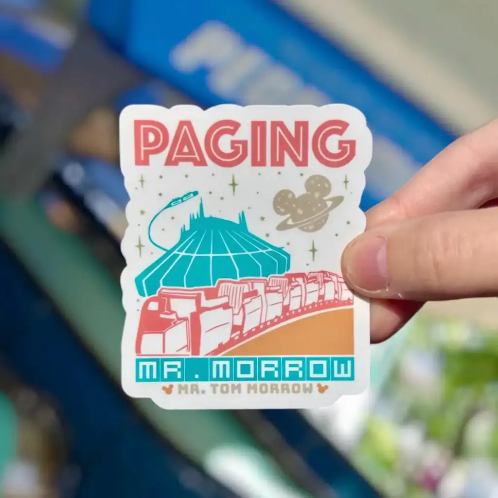 Colorful sticker with spaceship, planets, and retro design elements, ideal for Disney fans.