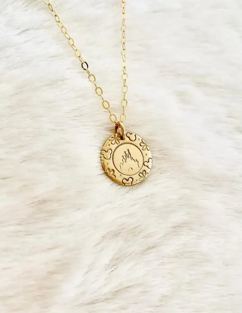 Gold Disney-inspired necklace with fiery silhouette charm and floral accents.