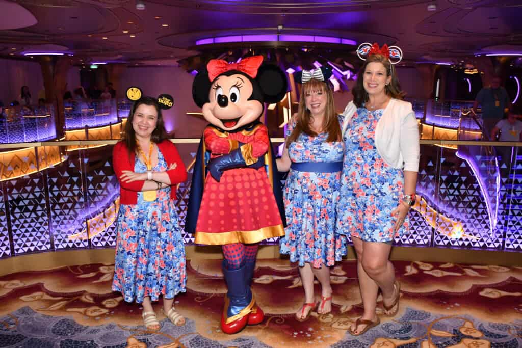 Minnie Mouse in colorful Disney cruise fashion with three women in floral dresses at Disney cruise e.