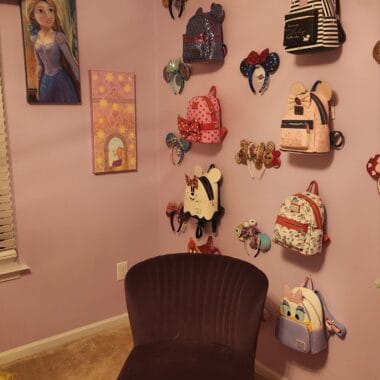 Collection of Disney-themed backpacks on a pink wall display.