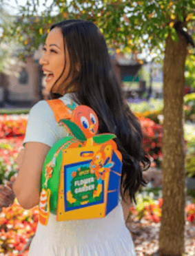 Woman with Disney Flounder and Ariel themed backpack outdoors.