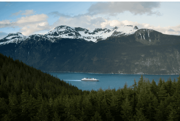 Beautiful mountain landscape with a cruise ship sailing on a serene lake. Perfect for travel and adv.