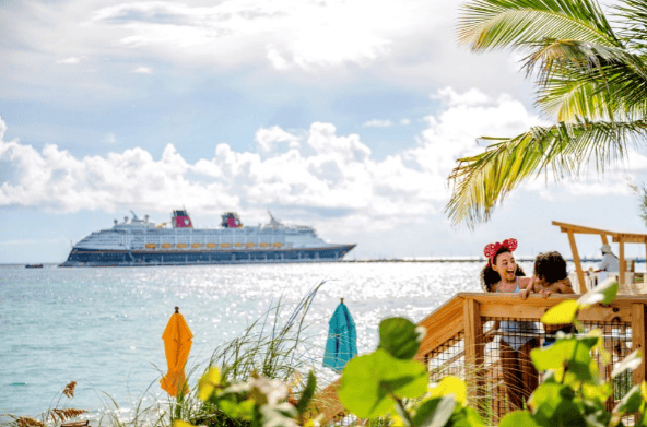 Family enjoying a Disney cruise vacation on a tropical beach with a cruise ship in the background.