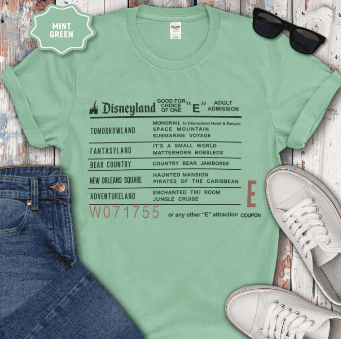 Green Disney-themed T-shirt featuring list of Disney park attractions and adventures.