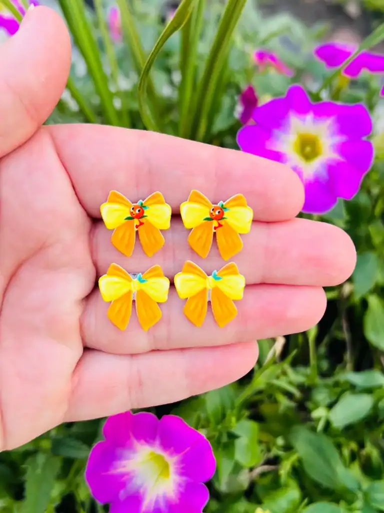 Bright yellow bow earrings with Disney character accents, perfect for fans.