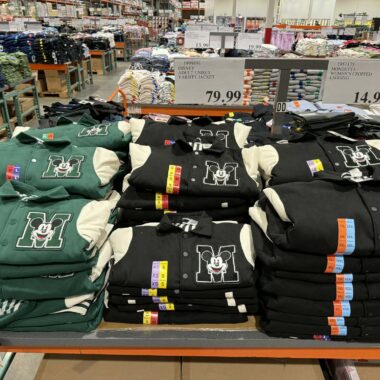 Disney Mickey Mouse hoodies in green, black, and gray at retail store.