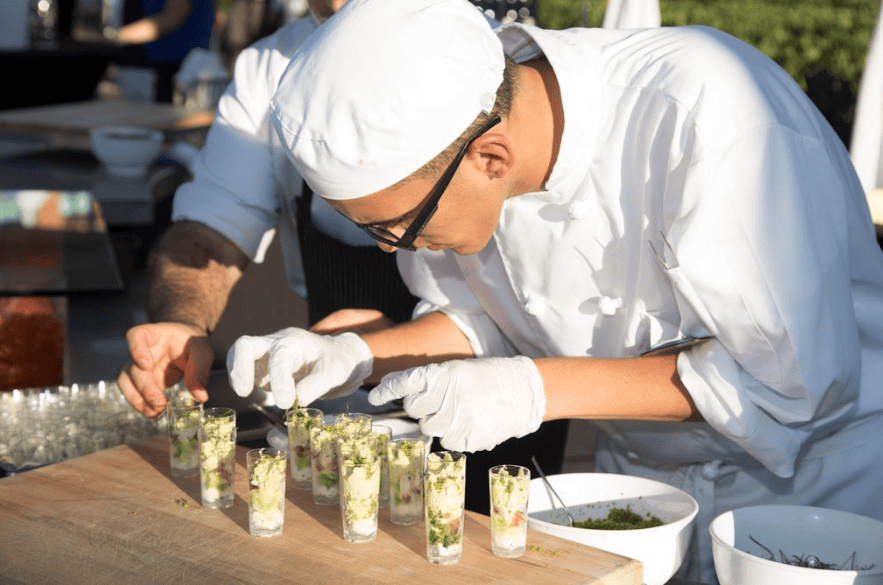 Chef plating sophisticated appetizers for food and wine event.