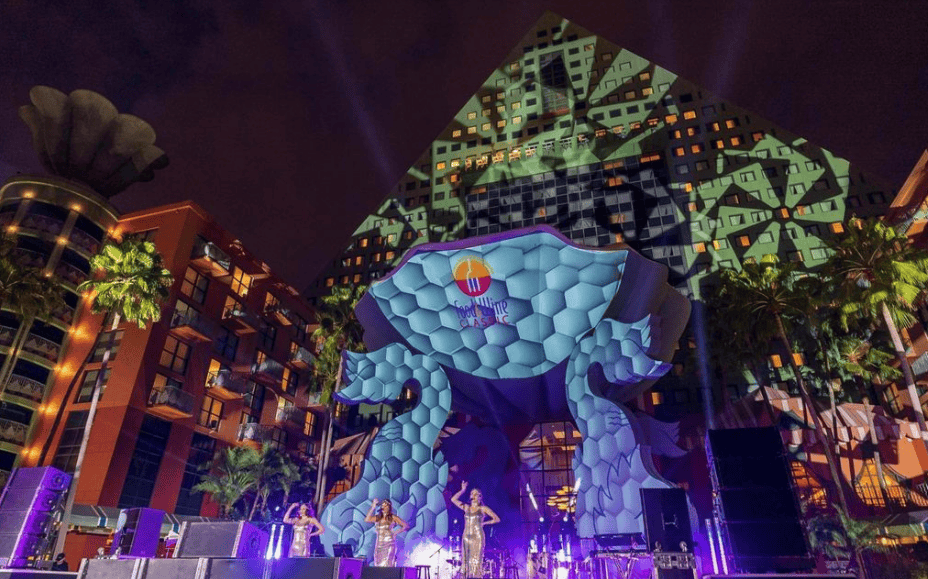 Vibrant outdoor stage at Disney Swan and Dolphin with colorful lighting and a giant animal sculpture.