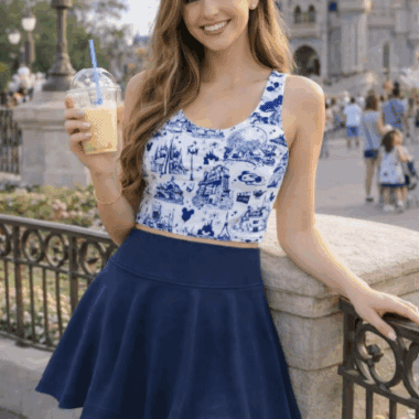 Woman in Disney-themed blue dress at Disney park with castle background.