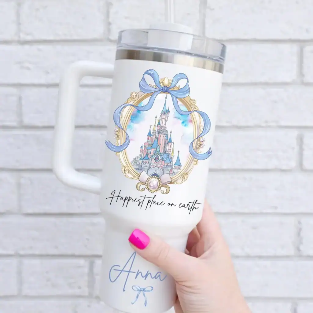 Disney castle travel mug with blue ribbon and "Happiest place on earth" text.
