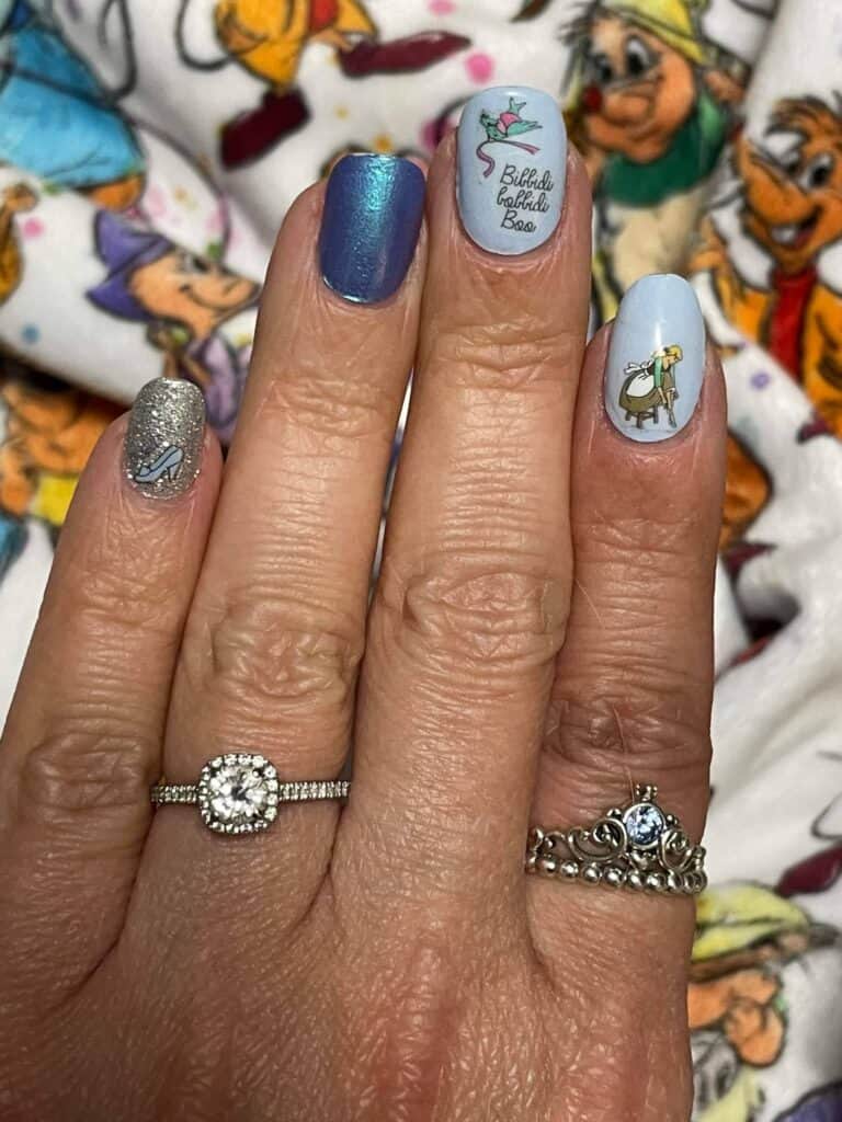 Disney-themed manicured nails with character art and glitter accents.
