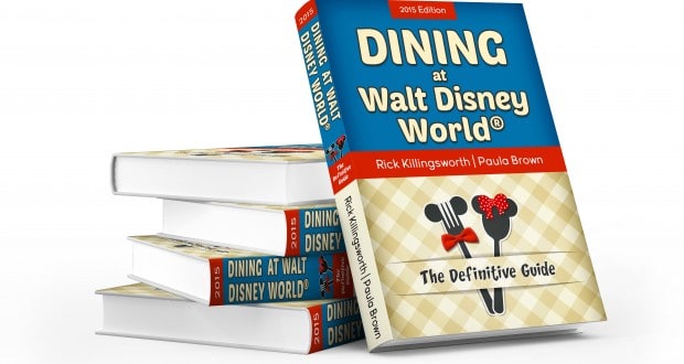 Stack of "Dining at Walt Disney World: The Definitive Guide" books with blue and beige covers, perfect for devoted Disney fans.