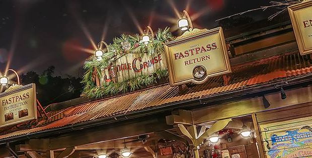 Jungle Cruise entrance at Disney World sparkling with holiday décor and FastPass+ signs, bustling with festive crowds at night.