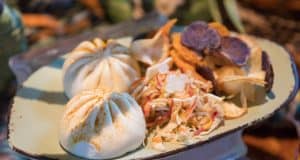 Steamed buns, veggie chips, and slaw with pearls on a green plate—one of Disney World's unique quick-service dishes.