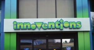 The colorful "Innoventions" sign welcomes guests above glass doors at Epcot’s vibrant, blue-and-green D-Zone entrance.