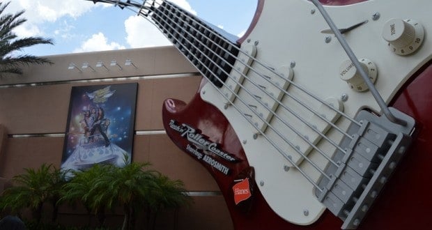 The iconic giant red and white guitar outside Rock 'n' Roller Coaster at Hollywood Studios, framed by palm trees and a mural.