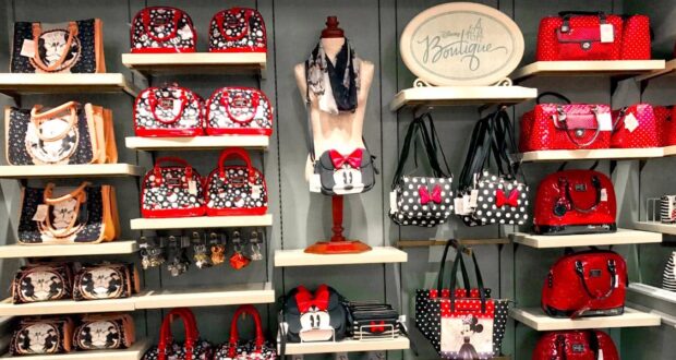 Minnie Mouse-inspired purses, bags, and wallets in classic red, black, and polka dot styles line the display shelves at Disney World.