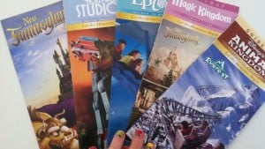 A handful of vibrant Walt Disney World park maps is fanned out, each held by dazzling, multicolored nails—ready for adventure!.