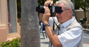 A cheerful guest snaps a photo near a palm tree, embracing the spirit of Disney’s Memory Maker at Walt Disney World.