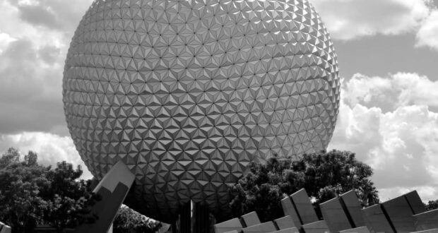 Spaceship Earth at Epcot in classic black and white, framed by lush trees and drifting clouds at Walt Disney World.