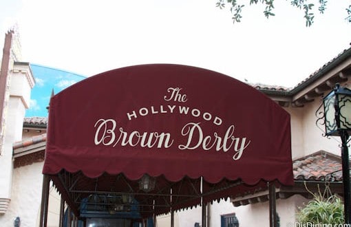 The Hollywood Brown Derby entrance at Disney's Hollywood Studios, marked by a burgundy awning with white script signage.