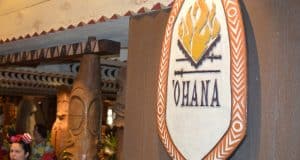 'Ohana restaurant sign glowing with a flame logo and lush tropical decor, bustling with guests at Walt Disney World.