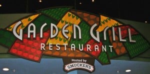 Garden Grill Restaurant sign at EPCOT, decked out in vibrant veggie designs with "Hosted by Smucker's" beneath the logo.