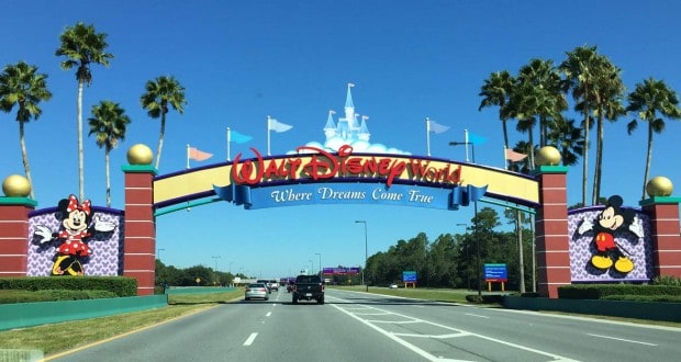 Cars drive toward the iconic Walt Disney World entrance, flanked by Mickey and Minnie Mouse, inviting fans to the magic ahead.