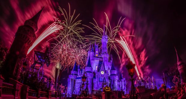 Cinderella Castle shines in pink and purple as fireworks erupt overhead, Halloween decor amplifying the Disney World magic.
