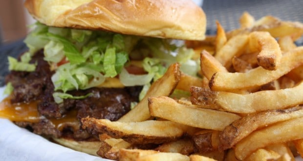 Classic cheeseburger with lettuce and tomato plus golden fries on a white plate—your Disney Parks-inspired meal awaits!.