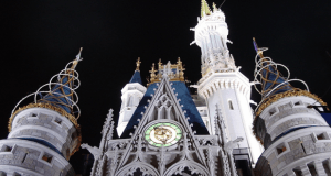 Cinderella Castle glowing at night, green clock shining above the entrance and soaring towers—Disney World’s iconic photo spot.