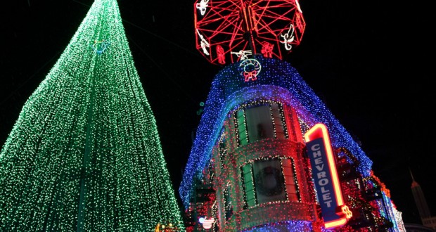 A giant Christmas tree and building glowing with vibrant lights, plus a red Chevrolet sign evoke classic Osborne Lights at Disney World.