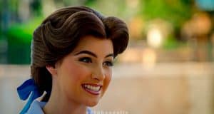 Belle greets guests with a radiant smile at Epcot, her brown hair styled beautifully with a charming blue ribbon—pure Disney magic.