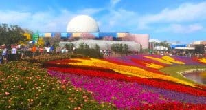 Vibrant flower beds and lush gardens frame Spaceship Earth’s iconic dome beneath clear blue skies at Epcot, Walt Disney World.