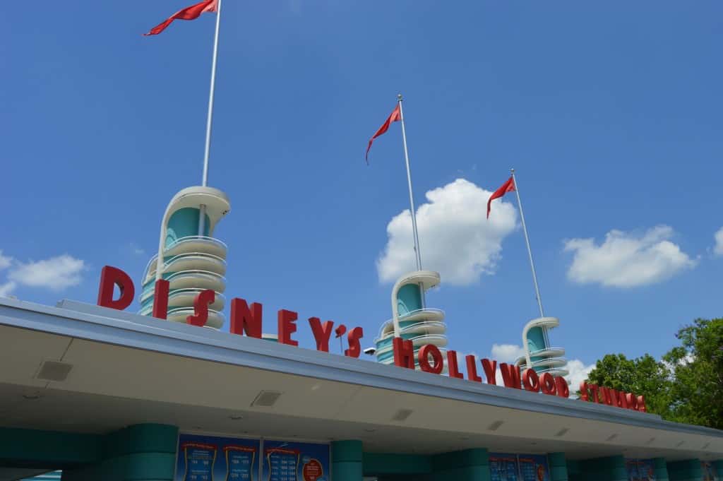 Disney’s Hollywood Studios entrance with bold red letters, three flagpoles, and a bright sky—your adventure begins here!.