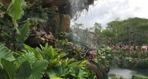 Verdant foliage and a cascading waterfall at Animal Kingdom, with guests immersed in the park’s thrilling attractions nearby.