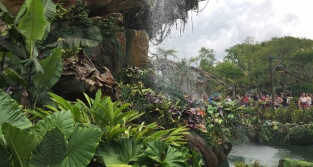 Verdant foliage and a cascading waterfall at Animal Kingdom, with guests immersed in the park’s thrilling attractions nearby.