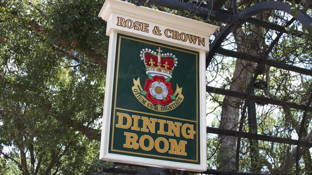 Rose & Crown Dining Room sign with crown and rose emblem welcomes visitors to Epcot’s UK Pavilion at Walt Disney World.