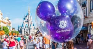 A purple Mickey Mouse balloon floats at Disney World, Cinderella Castle rising behind it as fans search for Hidden Mickeys in the crowd.