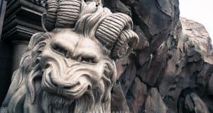 Majestic lion statue with ram horns, like the mythical decor at Disney World’s immersive themed restaurants, rocky and dramatic backdrop.