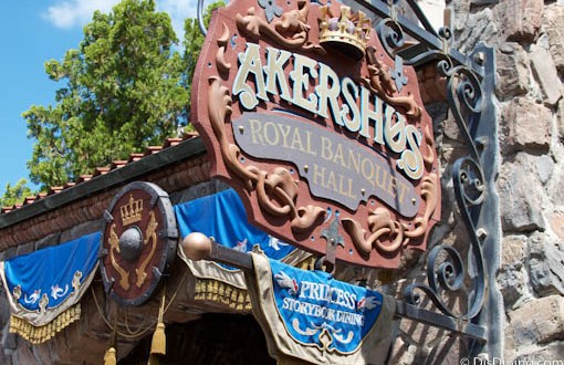 Akershus Royal Banquet Hall with blue banners invites guests to dine with Disney Princesses in a storybook castle setting.