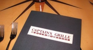 Captain’s Grille menu on a table at Disney’s Yacht Club Resort, featuring forks and compass rose designs in the nautical setting.