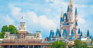 Cinderella Castle and Main Street entrance with clock tower, set against blue skies and clouds—Disney magic awaits your adventure.