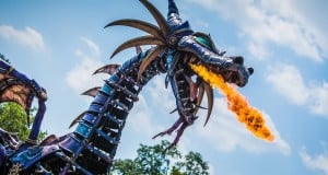 Maleficent’s towering dragon animatronic breathes real fire as it dazzles guests in a Disney World parade beneath sunny skies.