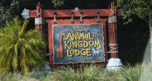 Disney’s Animal Kingdom Lodge sign with giraffe and zebra art in lush greenery—where Disney magic meets African wildlife adventure.