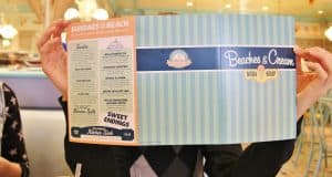 Guest conceals their face behind a Beaches & Cream Soda Shop menu at Disney’s Beach Club Resort, inside the lively diner.