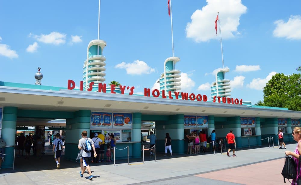 Disney’s Hollywood Studios entrance welcomes guests under sunny blue skies, buzzing with excitement at Walt Disney World.