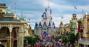 Guests fill Main Street, U.S.A., heading toward Cinderella Castle at Magic Kingdom under a cloudy sky.