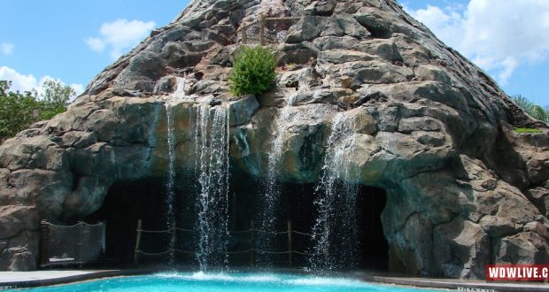 Inviting grotto with waterfalls cascading into a vibrant blue pool, echoing the signature swim spots found at Disney resort hotels.