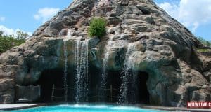 Exciting waterfalls cascade over rocky cliffs into a sparkling pool under the sun at Disney’s Caribbean Beach Resort.